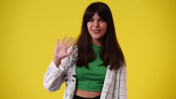 黄色の背景にこんにちは手を振っている1人の女の子の4Kスローモーションビデオ 感情の概念 — ストック動画