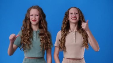 4k slow motion video of two twin girls showing thumb up and down. Concept of emotions.