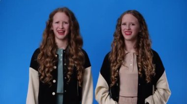 4k slow motion video of twin girls gesturing no over blue background. Concept of emotions.