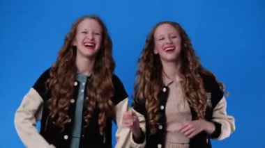4k slow motion video of twin girls dancing over blue background. Concept of emotions.
