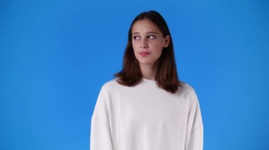 4k slow motion video of one girl showing silence sign over blue background. Concept of emotions.