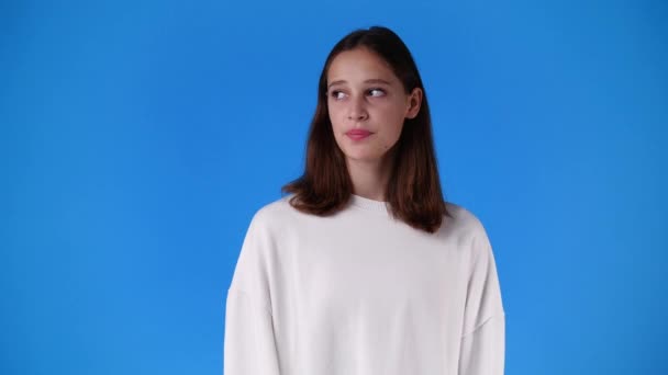 青の背景の上に無音サインを示す1人の少女の4Kスローモーションビデオ 感情の概念 — ストック動画