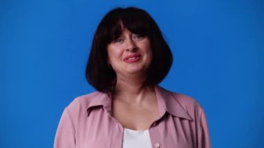 4k slow motion video of one woman with positive emotions over blue background. Concept of emotions.