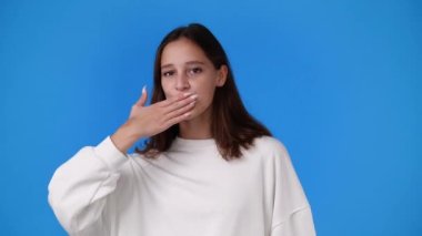 4k slow motion video of one girl sending an air kiss on blue background. Cocnept of emotions.