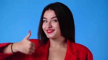 4k slow motion video of one girl smiling and showing thumbs up on blue background. Concept of emotions.