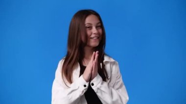 4k slow motion video of excited girl clapping in hands on blue background. Concept of emotions.