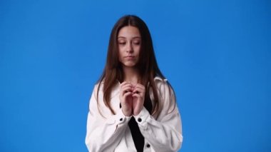 4k slow motion video of one girl thinking about something on blue background. Concept of emotions.