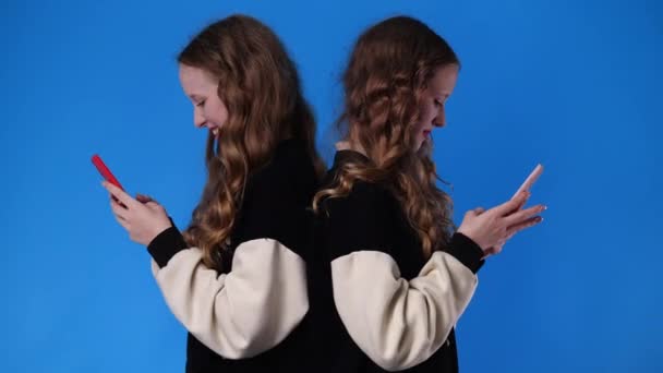 Wideo Bliźniaczek Korzystających Telefonów Niebieskim Tle Pojęcie Emocji — Wideo stockowe
