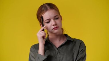 4k slow motion video of a girl thinking about something over yellow background. Concept of emotions.