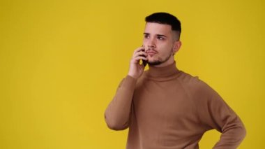 4k video of one man using phone over yellow background. Concept of emotion.