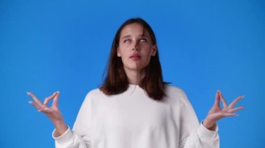 Bir kızın mavi arka plandaki bir video için poz verdiği 4K video. Duyguların kavramı.