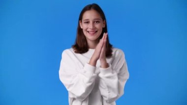 4k slow motion video of excited girl clapping in hands on blue background. Concept of emotions.