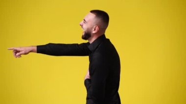 4k video of one man laughing and points to someone on yellow background. Concept of emotions.