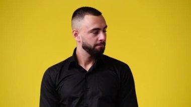 Sarı arka planda sessizlik işareti gösteren bir adamın 4K videosu. Duyguların kavramı.