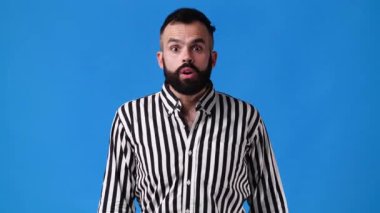 4k slow motion video of one man in surprised and closes his mouth over blue background. Concept of emotions.