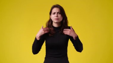 4k slow motion video of one woman waving her hands and showing that she didnt do anything over yellow background. Concept of emotions.