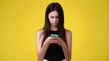 4k video of one girl with a negative facial expression typing text over yellow background. Concept of emotions.
