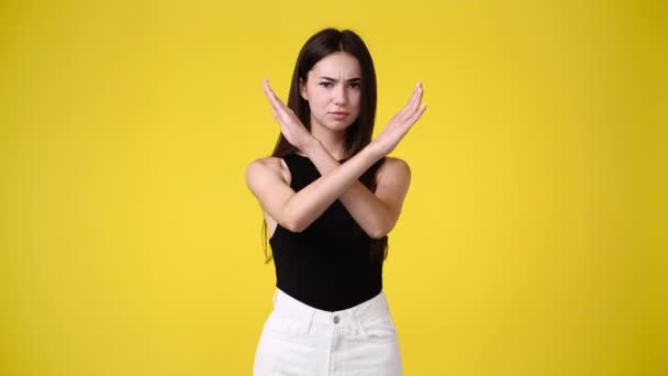 腕を交差し 黄色の背景の上に何かに否定的に応答する1人の少女の4Kビデオ 感情の概念 — ストック動画