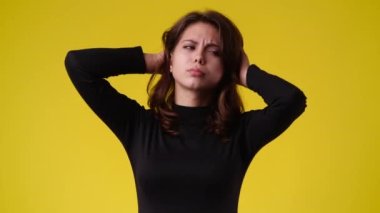 4k video of one girl touches her hair and wonders over yellow background. Concept of emotions.