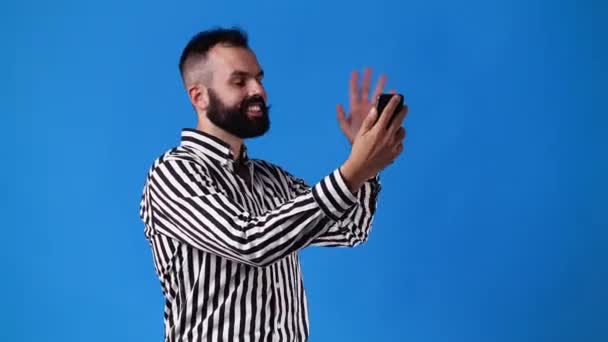 青い背景の誰かと電話で話してる男の4Kビデオ 感情の概念 — ストック動画