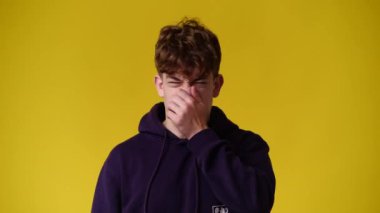 4k video of one man closes the nose against the smell over yellow background. Concept of emotions.