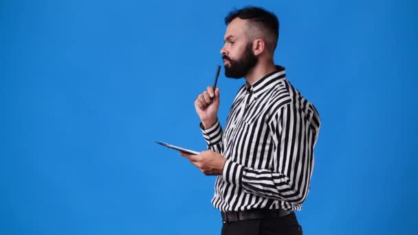 1人の男の4Kビデオはペンで何かを計画し 青い背景に注意してください 感情の概念 — ストック動画