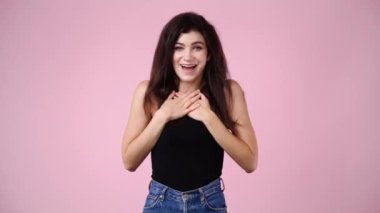 4k video of one girl smiling sweetly and holding his cheeks for a video over pink background. Concept of emotions.