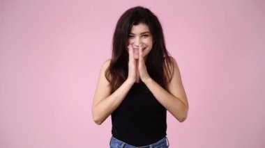 4k video of one girl claps his hands and smiling over pink background. Concept of emotions.