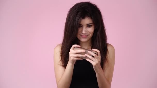 Видео Одной Девушки Играет Телефоне Розовом Фоне Концепция Эмоций — стоковое видео