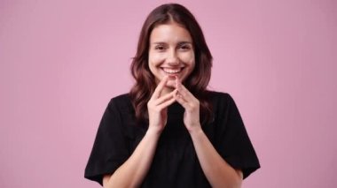 Pembe arka planda kurnaz yüz ifadesi olan bir kızın 4K videosu. Fikirleri olan kız kavramı.