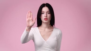 Sarı arka planda dur işareti gösteren bir kızın 4K videosu. Duyguların kavramı.