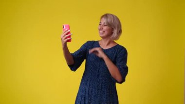4k video of one woman talking with someone on the phone and touching her hair over yellow background. Concept of emotions.