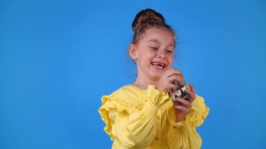 4k slow motion video of one young girl playing with a toy and smiling over blue background. Concept of emotions.