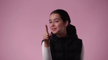 Genç bir kızın 4K videosu pembe arkaplan üzerinden birini aramak istiyor. Duyguların kavramı.