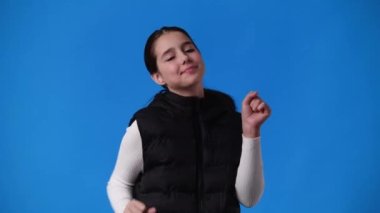 Mavi arka planda dans eden genç bir kızın 4K videosu. Duyguların kavramı.