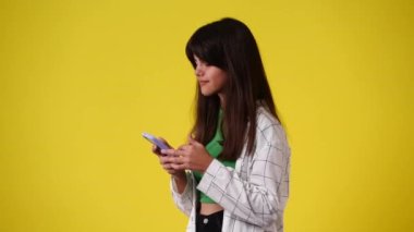 4k video of one girl scrolling messenger and showing thumbs up over yellow background. Concept of emotions.