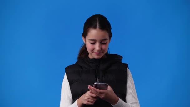 Video One Young Girl Typing Text Smiles Blue Background Concept — Vídeos de Stock