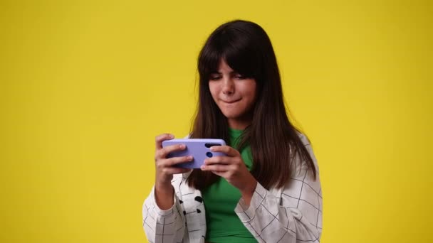 一个女孩的4K视频是通过黄色背景的电话播放的 情绪的概念 — 图库视频影像