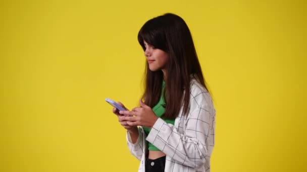 4K视频一个女孩滚动信使和显示大拇指在黄色背景 情绪的概念 — 图库视频影像