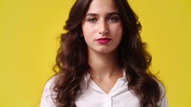 Yüzünde negatif ifade olan bir kızın sarı arka planda baş parmağını aşağı gösteren 4K videosu. Duyguların kavramı.