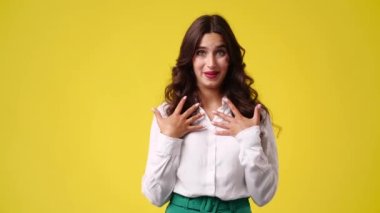 Kollarını kavuşturup sarı arka planda bir şeye negatif tepki veren bir kızın 4K videosu. Duyguların kavramı.