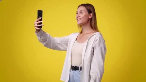 Video Una Mujer Hace Video Teléfono Sobre Fondo Amarillo Concepto — Vídeos de Stock