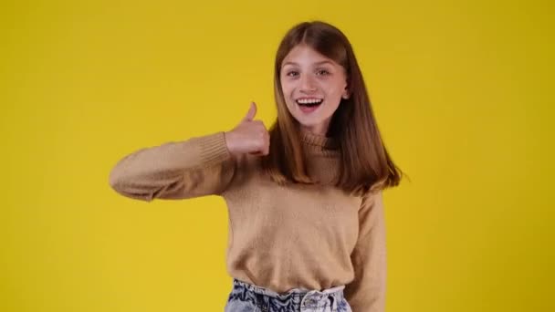 Видео Одной Девушки Показывающей Большие Пальцы Вверх Улыбающейся Желтом Фоне — стоковое видео
