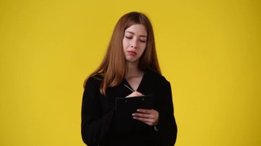 4k video of one girl taking notes over yellow background. Concept of emotions.