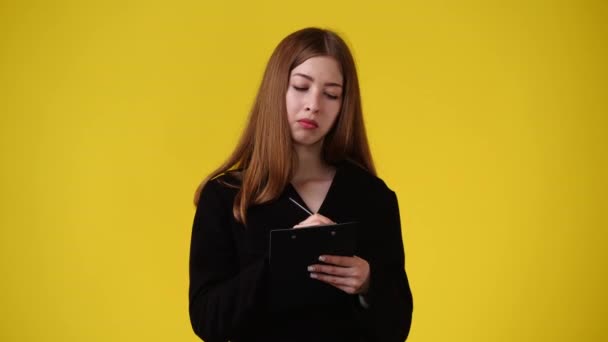 一个女孩在黄色背景下做笔记的4K视频 情绪的概念 — 图库视频影像