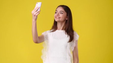 Sarı arka planda güzel bir kızın selfie çektiği 4K video. Duyguların kavramı.