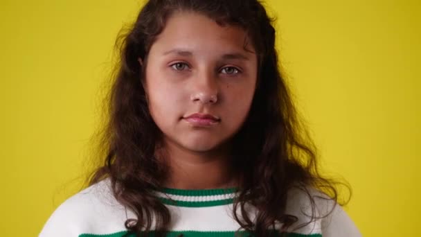黄色の背景の上にビデオをポーズする1人の女の子の4Kビデオ 感情の概念 — ストック動画