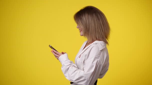 Video Chica Usando Teléfono Sobre Fondo Amarillo Concepto Emoción — Vídeos de Stock