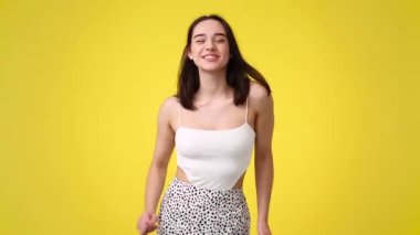 Bir kızın 4K videosu sarı arka plandaki bir şey için çok heyecanlı. Duyguların kavramı.