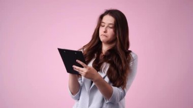 4k video of one girl taking notes over pink background. Concept of emotions.